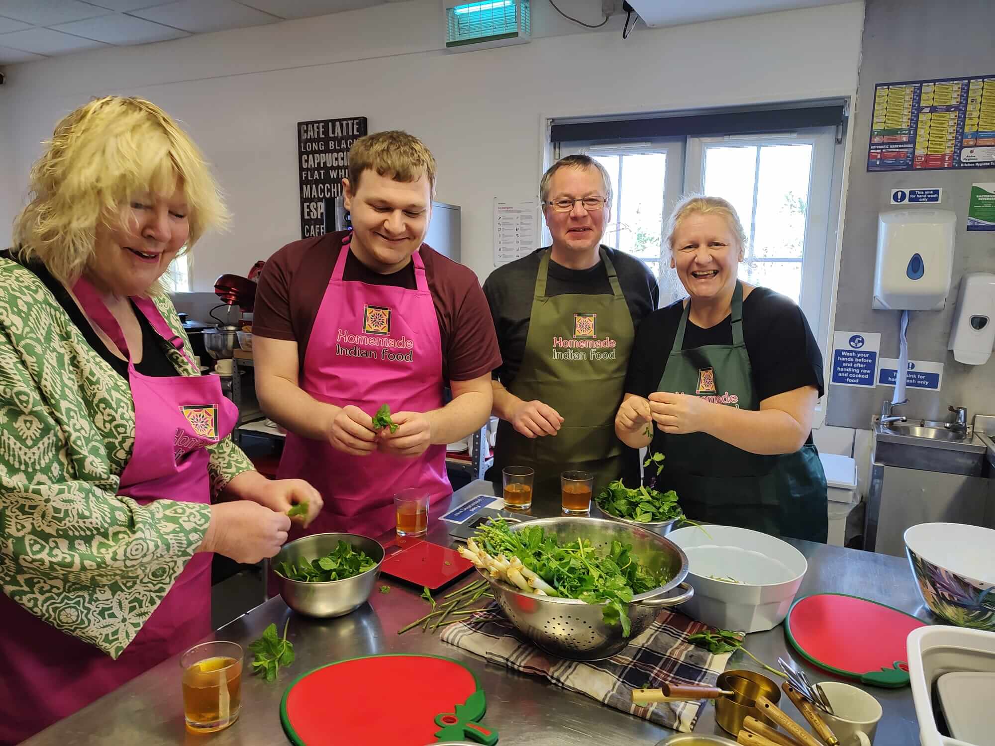 Guests in HIF aprons laughing as they pick fresh coriander together