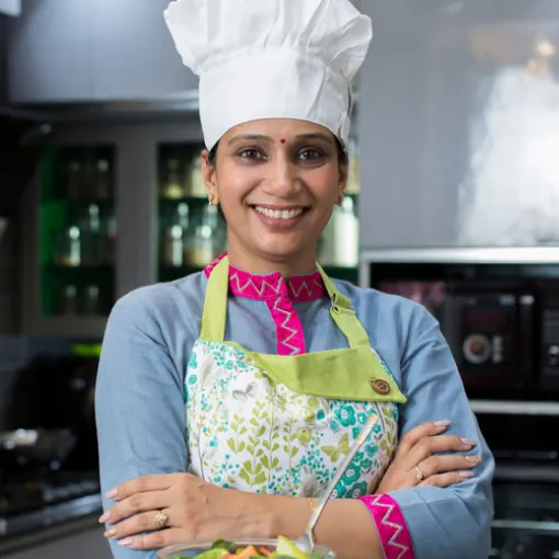 A Kitchen Queen in her chef hat and apron
